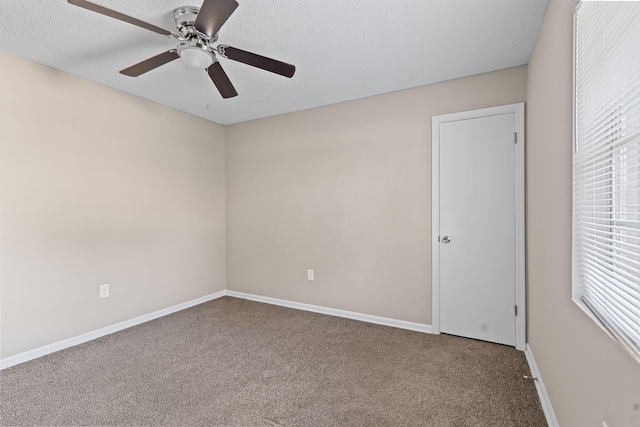 carpeted spare room featuring a textured ceiling, ceiling fan, and baseboards