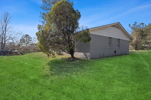 view of home's exterior with brick siding and a yard