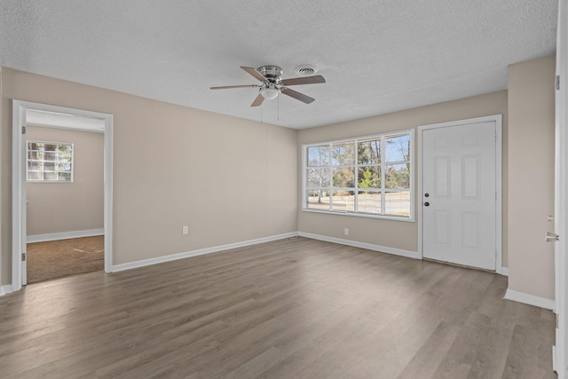 interior space with a textured ceiling, baseboards, and wood finished floors