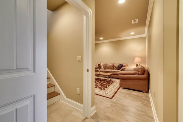 hallway with ornamental molding and light hardwood / wood-style floors