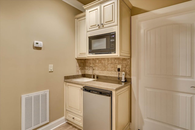 kitchen with sink, dishwasher, black microwave, cream cabinets, and decorative backsplash