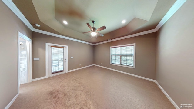 empty room featuring ornamental molding, a raised ceiling, ceiling fan, and carpet flooring