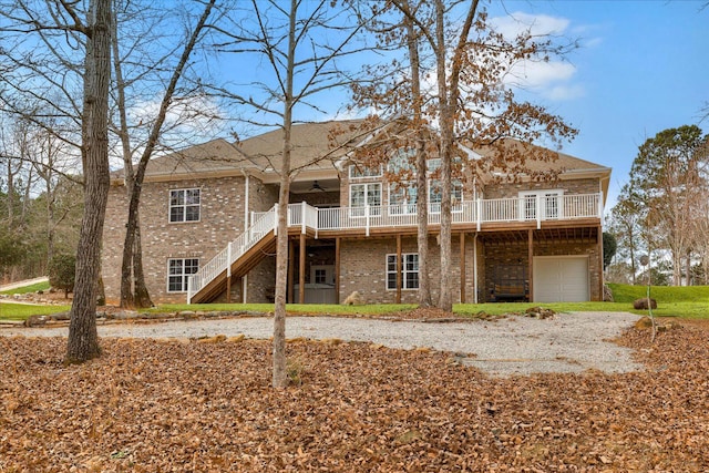 rear view of house featuring a garage, ceiling fan, and a deck