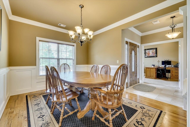 dining space featuring an inviting chandelier, ornamental molding, and light wood-type flooring