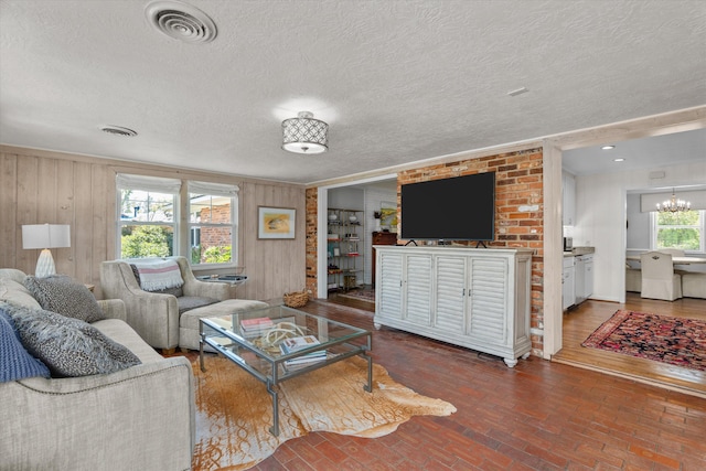 748 Mcclure Dr, Augusta, GA 30909 - living area featuring wood walls, a textured ceiling, a chandelier, and brick floors