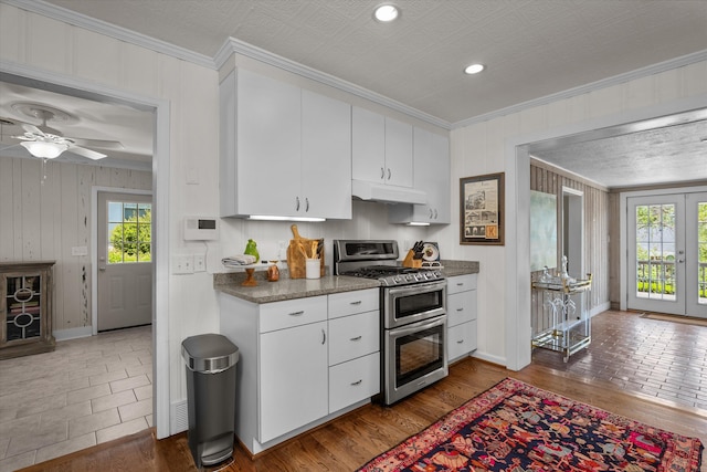 748 Mcclure Dr, Augusta, GA 30909 - kitchen with double oven range, plenty of natural light, under cabinet range hood, crown molding, and white cabinets
