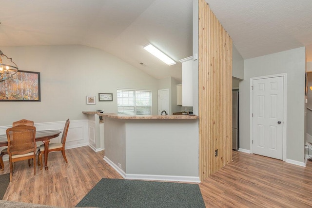 510 Sweet Meadow Dr, Grovetown, GA 30813 - kitchen featuring wood finished floors, vaulted ceiling, white cabinets, a chandelier, and a wainscoted wall