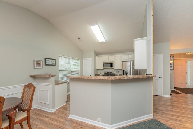 510 Sweet Meadow Dr, Grovetown, GA 30813 - kitchen featuring appliances with stainless steel finishes, lofted ceiling, light wood-style flooring, white cabinetry, and a peninsula