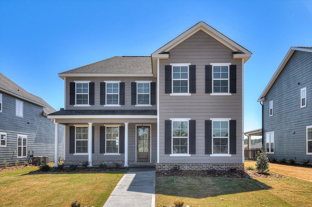 traditional home featuring a front yard, a porch, central AC unit, and roof with shingles