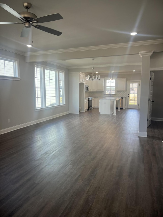 unfurnished living room with baseboards, a sink, dark wood finished floors, and crown molding