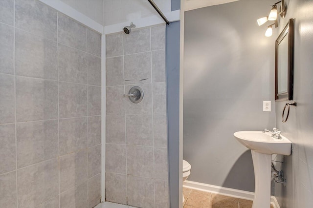 bathroom with tile patterned floors, toilet, a tile shower, and sink