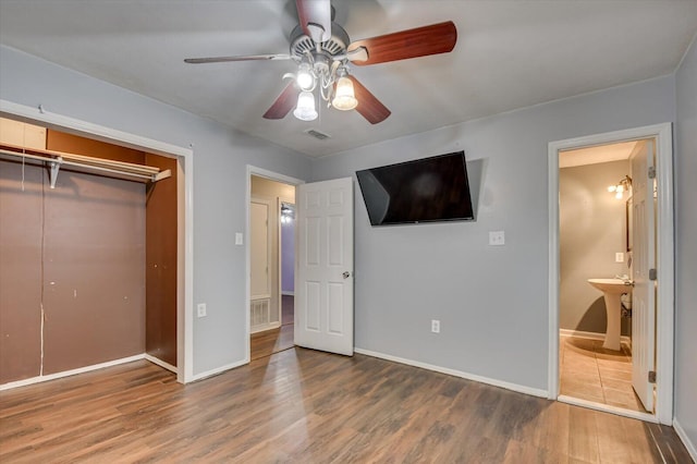 unfurnished bedroom with ceiling fan, a closet, ensuite bathroom, and wood-type flooring