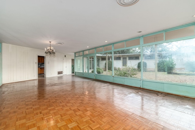 unfurnished room featuring light parquet flooring and a notable chandelier