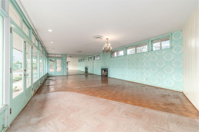 unfurnished room featuring french doors, light parquet floors, and an inviting chandelier