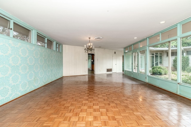 unfurnished room with a notable chandelier and light parquet flooring