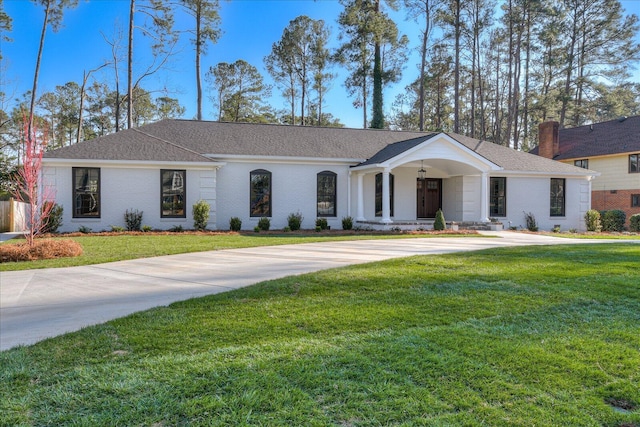 ranch-style house with a shingled roof, a front yard, brick siding, and driveway