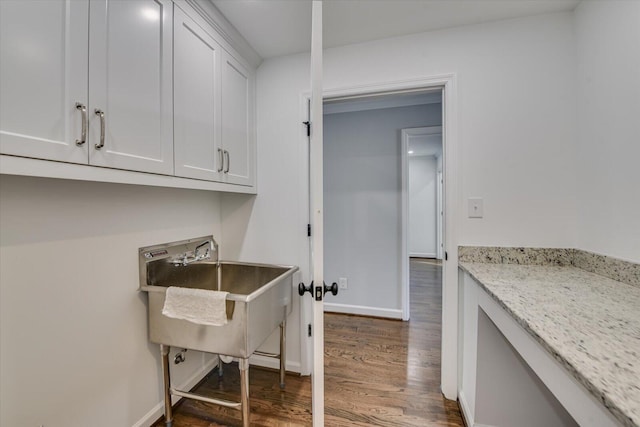 laundry area featuring a sink, baseboards, and wood finished floors