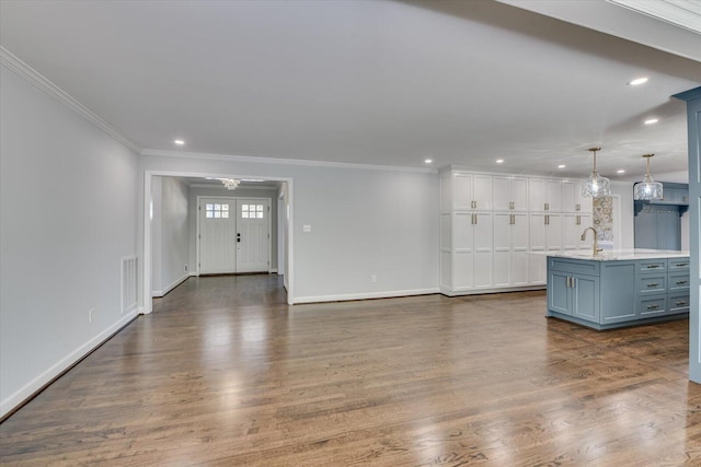 unfurnished living room featuring ornamental molding, dark wood-type flooring, a sink, and baseboards