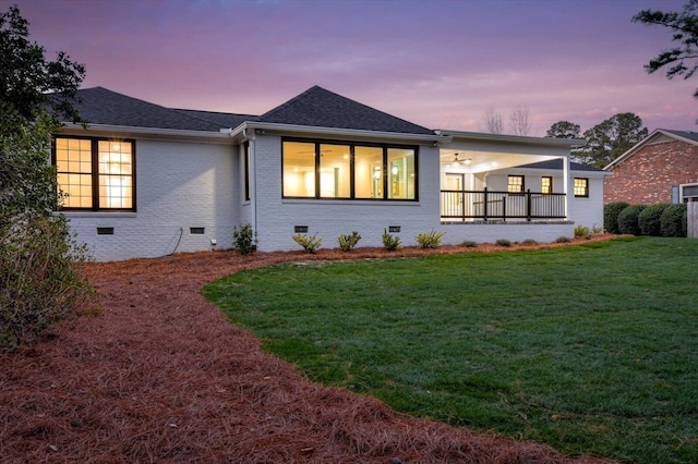 view of front facade with crawl space, a shingled roof, a front yard, and brick siding