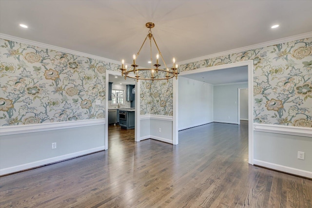 unfurnished dining area featuring a wainscoted wall, crown molding, dark wood finished floors, and wallpapered walls