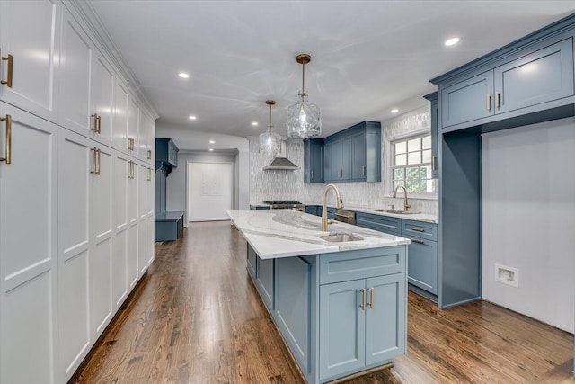 kitchen featuring dark wood finished floors, a sink, backsplash, and wall chimney exhaust hood