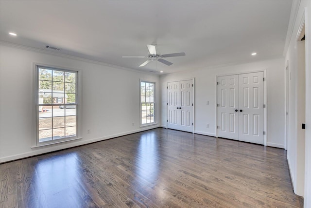 spare room with ornamental molding, visible vents, and wood finished floors