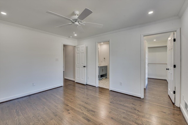 unfurnished bedroom with recessed lighting, wood finished floors, baseboards, a walk in closet, and crown molding