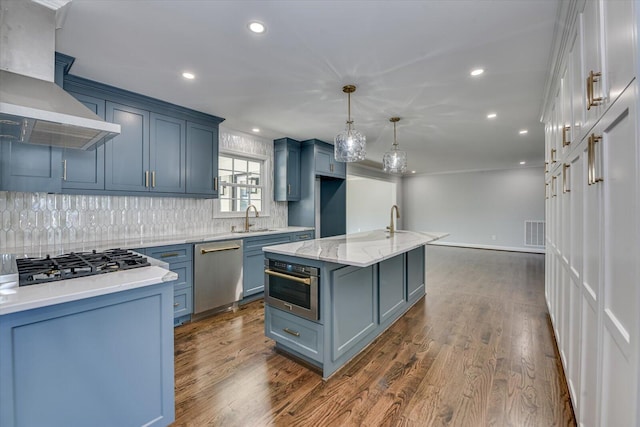 kitchen featuring visible vents, appliances with stainless steel finishes, dark wood-type flooring, a sink, and wall chimney exhaust hood