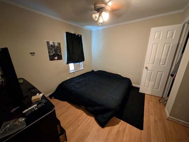 bedroom featuring a ceiling fan, crown molding, baseboards, and wood finished floors