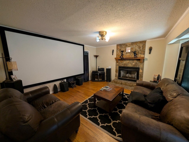 cinema with a textured ceiling, wood finished floors, a fireplace, and ornamental molding