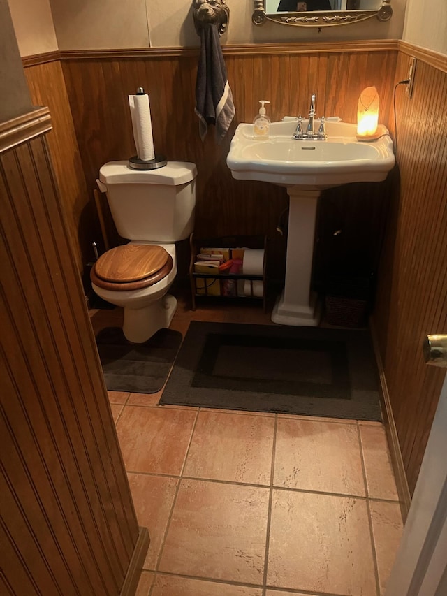 bathroom featuring wooden walls, toilet, and a wainscoted wall