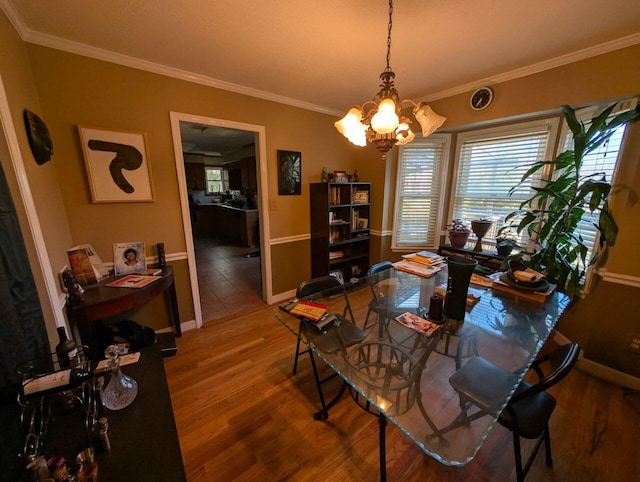 dining space featuring a notable chandelier, crown molding, baseboards, and wood finished floors