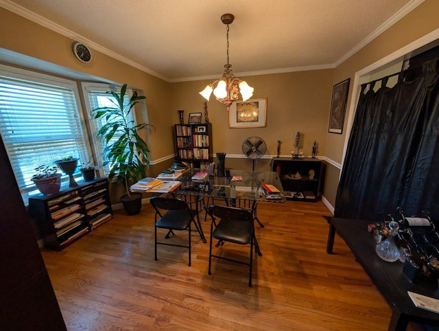 dining area with a notable chandelier, crown molding, and wood finished floors