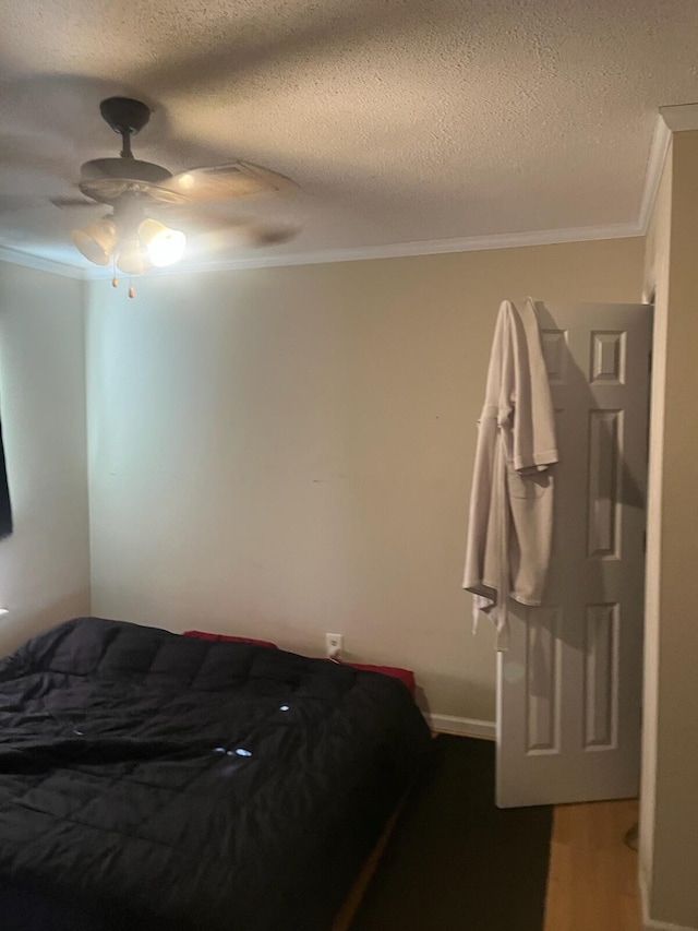 bedroom featuring a textured ceiling, wood finished floors, ceiling fan, and ornamental molding