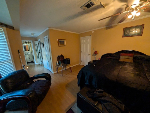 bedroom with visible vents, crown molding, baseboards, and wood finished floors