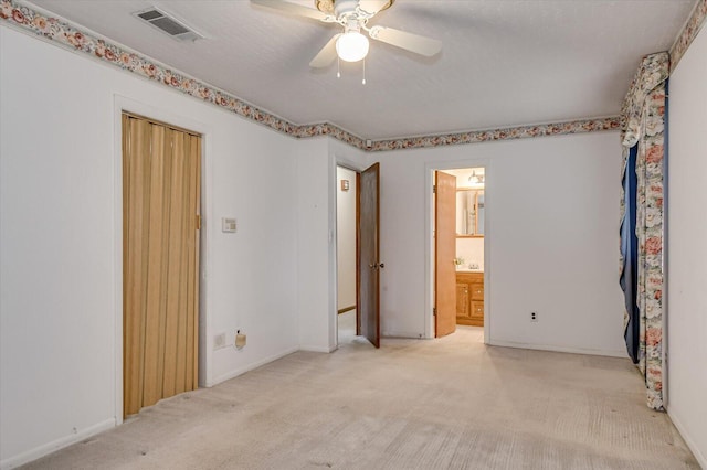 unfurnished bedroom with visible vents, carpet, ensuite bath, and a ceiling fan