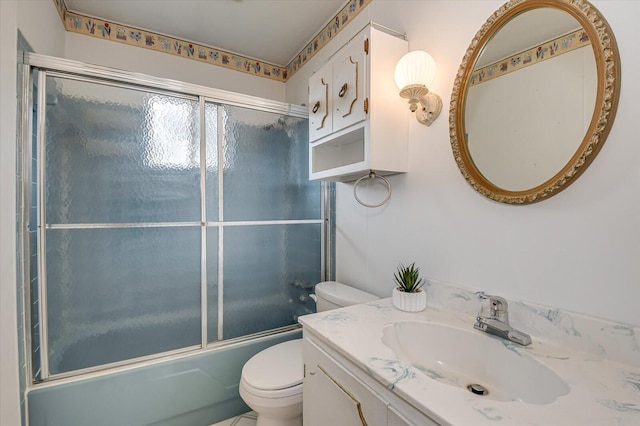 full bathroom featuring combined bath / shower with glass door, toilet, and vanity