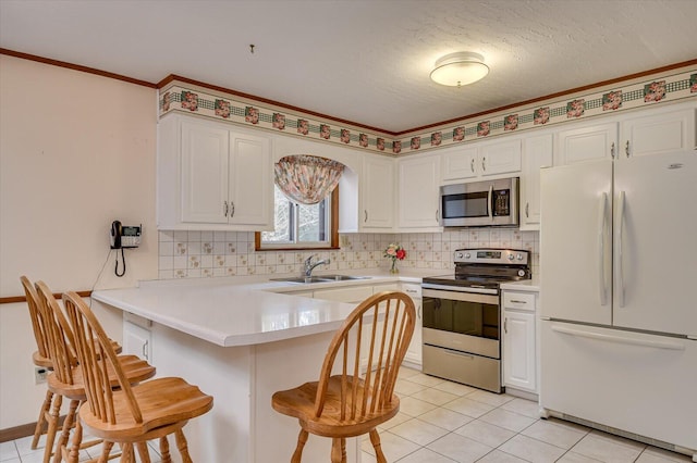 kitchen with a breakfast bar, a peninsula, backsplash, and appliances with stainless steel finishes