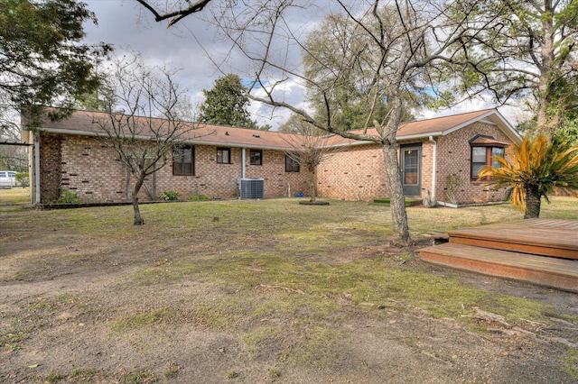 back of house featuring brick siding, central air condition unit, and a lawn