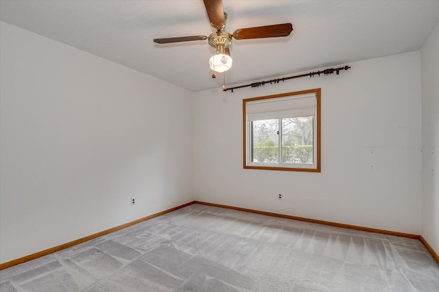 spare room featuring baseboards, light carpet, and a ceiling fan