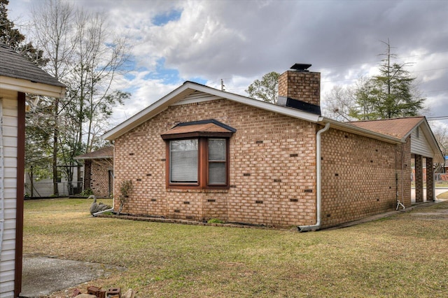 view of property exterior with brick siding, a lawn, and a chimney