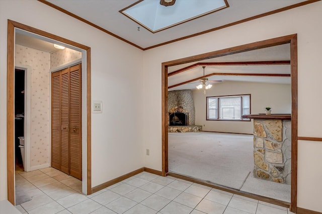 unfurnished room featuring lofted ceiling with skylight, light tile patterned floors, a fireplace, and baseboards