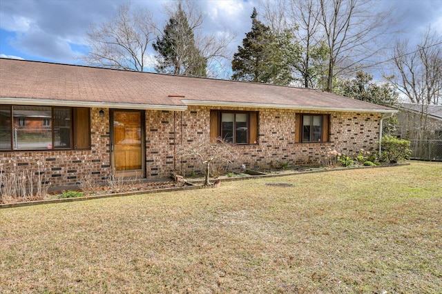 ranch-style house featuring brick siding, a front yard, and roof with shingles