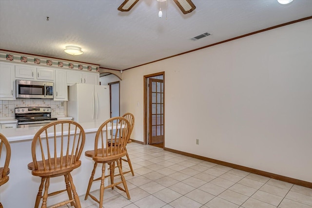 kitchen featuring visible vents, white cabinetry, stainless steel appliances, crown molding, and light countertops