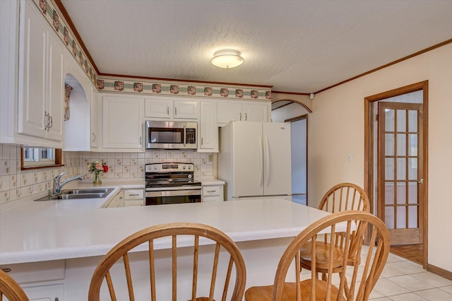 kitchen featuring a sink, appliances with stainless steel finishes, a peninsula, crown molding, and light countertops