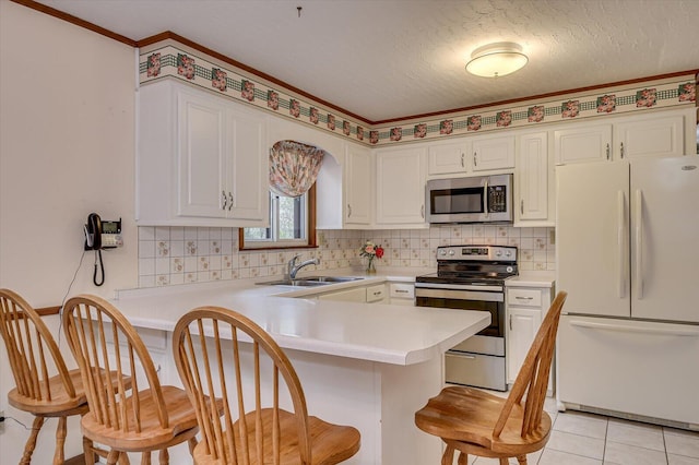 kitchen featuring a peninsula, a sink, light countertops, appliances with stainless steel finishes, and backsplash