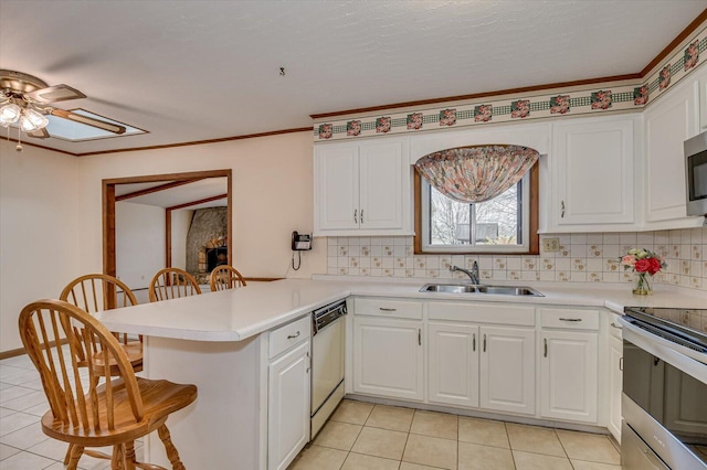 kitchen featuring a kitchen breakfast bar, appliances with stainless steel finishes, a peninsula, white cabinetry, and a sink