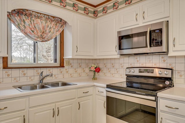 kitchen with light countertops, decorative backsplash, appliances with stainless steel finishes, white cabinets, and a sink