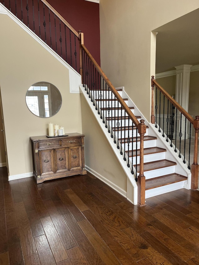 staircase featuring hardwood / wood-style floors, a high ceiling, and baseboards