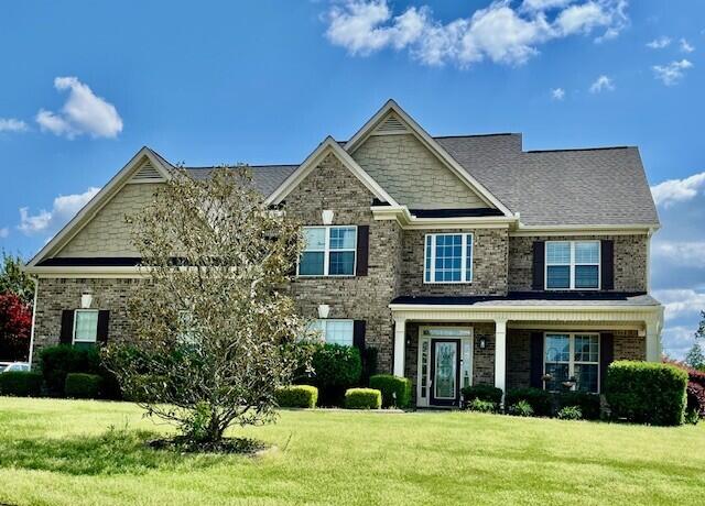 craftsman inspired home featuring brick siding and a front yard